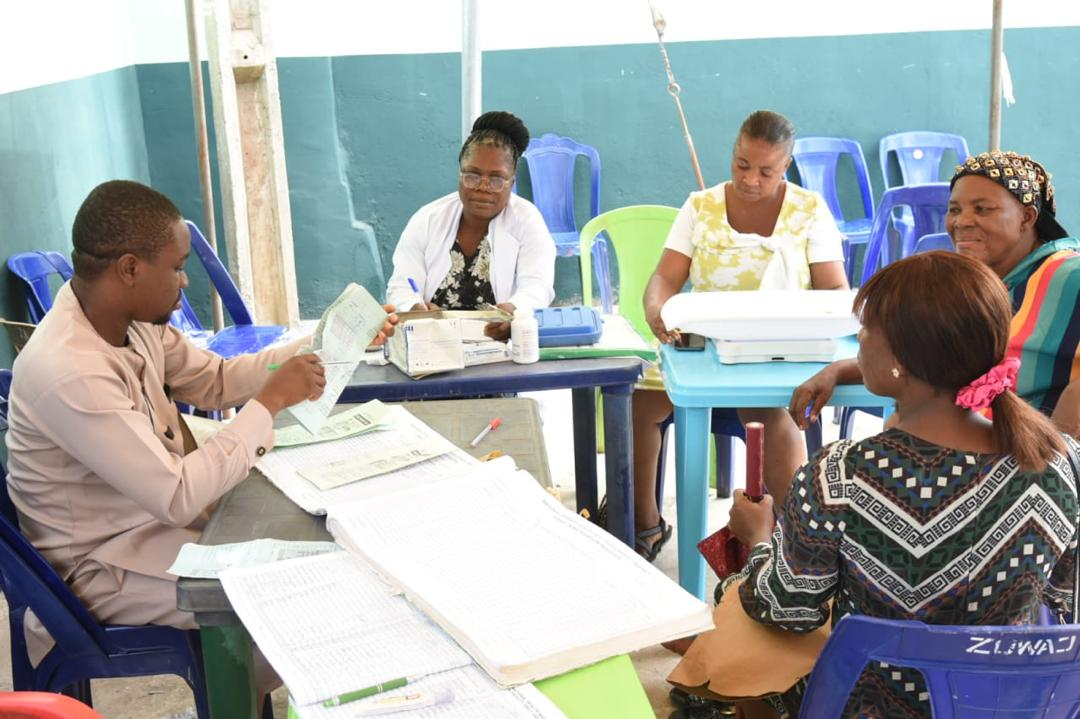 Mission registration and screening teams working with community members at outdoor clinic tables in Abia State during the 2025 mission.
